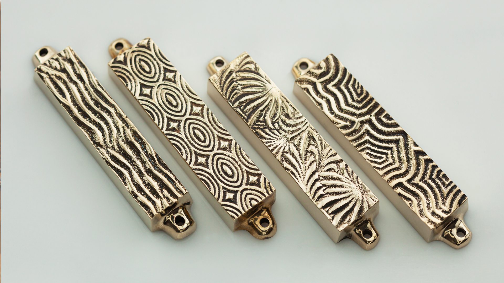 Four small brass mezuzah cases with art deco patterns inspired by classic shapes and mezuzah trace, designed by MI POLIN design