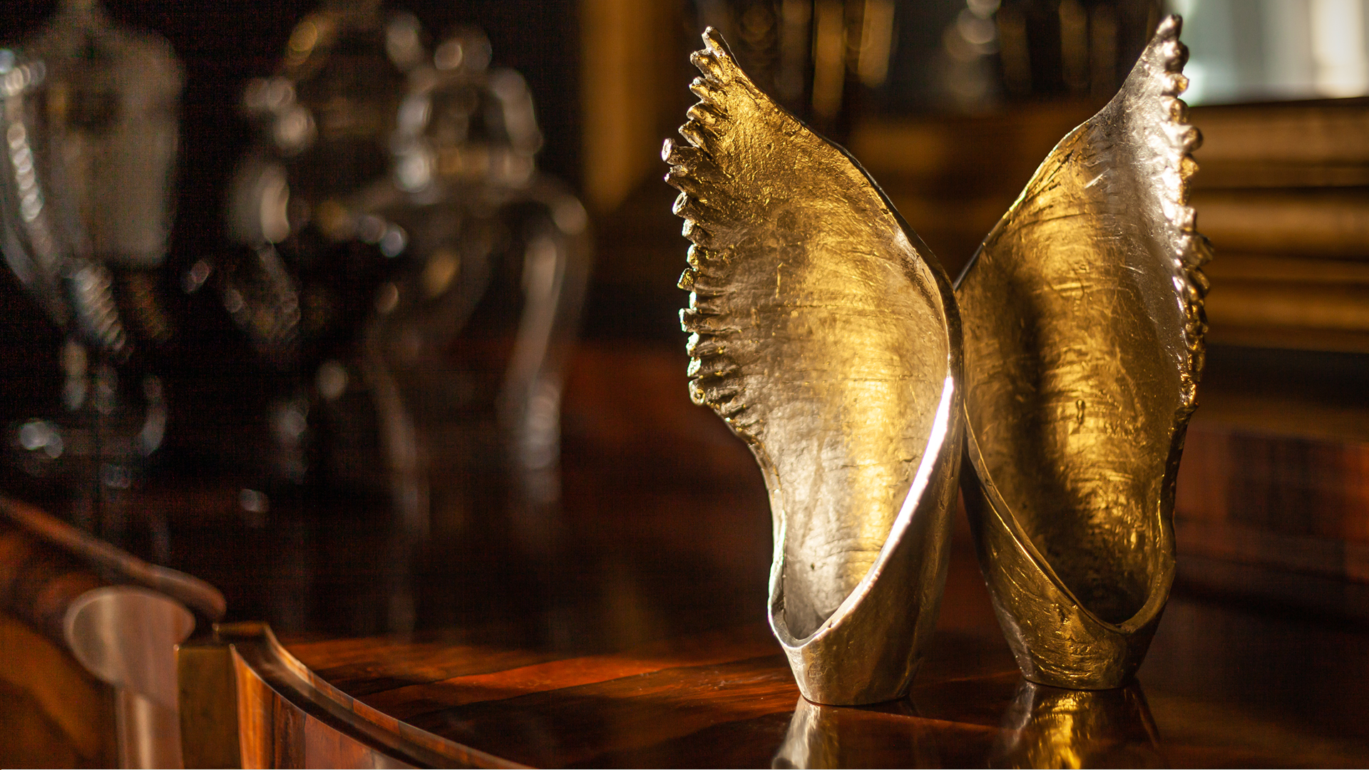 A pair of ornate gold-colored Sabbath candle holders inspired by the song Shalom Aleichem, placed on a polished surface, designed by MI POLIN design